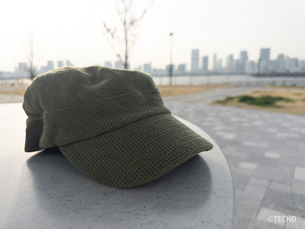 補正前の画像：iPhoneで撮影したままのDNG（RAW）データ。全体的に露出が少し暗く、帽子の色や背景の街並みが沈んでいる状態。