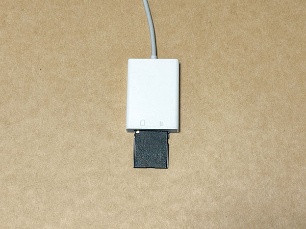 カメラで撮影したSDカードをリーダーに挿入している