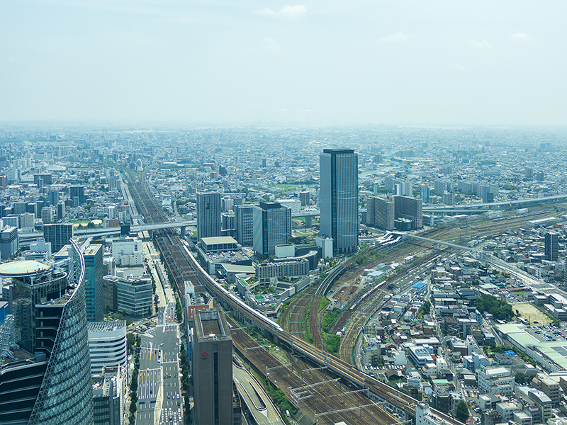 スカイプロムナード南側から見下ろす名古屋市街地。鉄道やビル群の先に名古屋港が見える風景。