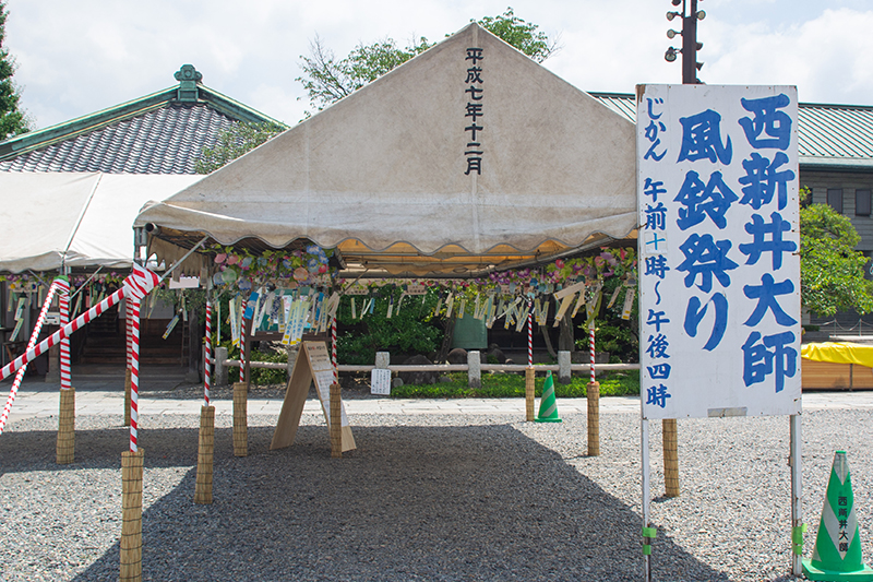西新井大師の風鈴祭りの案内看板と展示エリア。日本各地から集められた風鈴が境内を彩る。