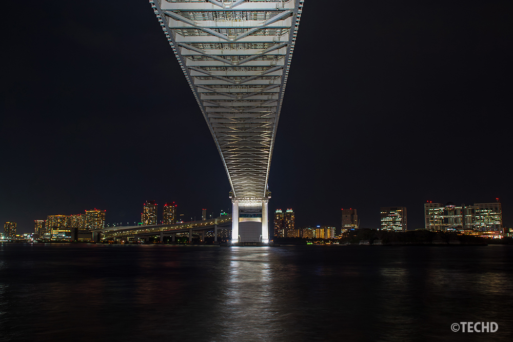 芝浦南ふ頭公園から撮影したレインボーブリッジ夜景。橋の真下から見上げる構図で、ライトアップされた橋と都心の高層ビル群が夜空に浮かび上がっている。