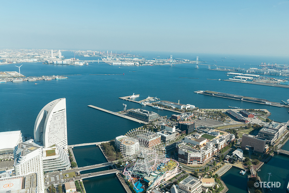 横浜ランドマークタワー・スカイガーデンから見た横浜港の昼景。観覧車やインターコンチネンタルホテル、ベイブリッジが広がる快晴のパノラマ。
