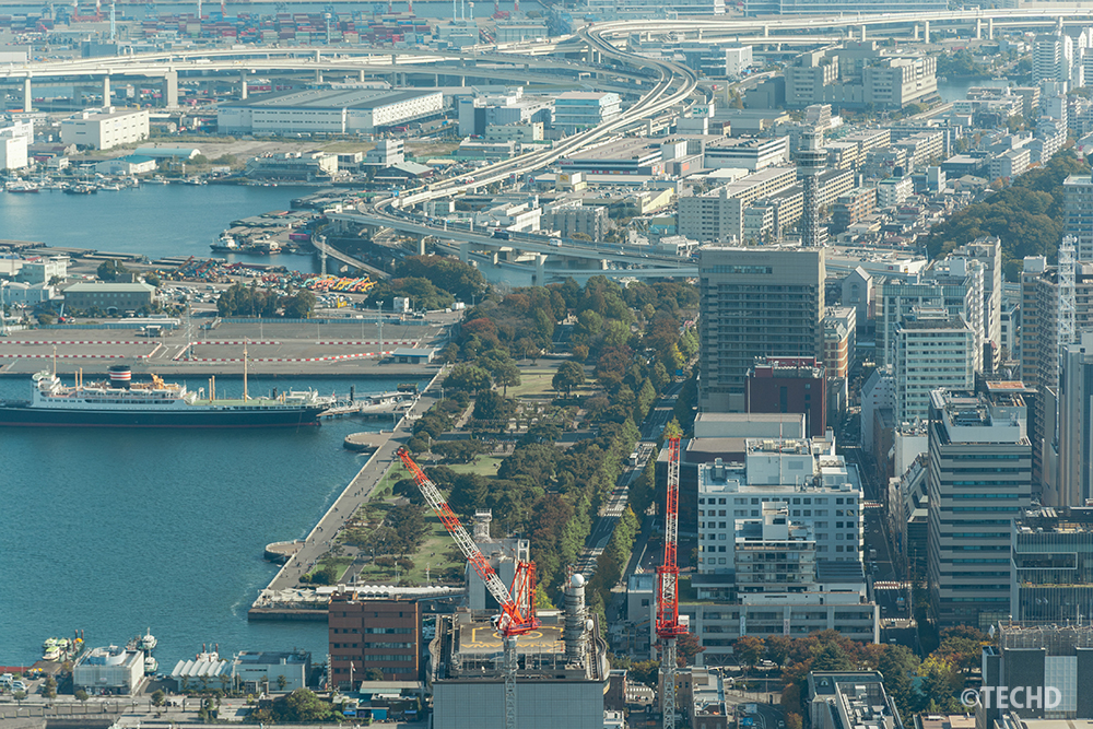 スカイガーデンから見た山下公園と横浜マリンタワー、横浜港周辺。緑地と海、高速道路が交わる横浜らしい海沿いの風景。