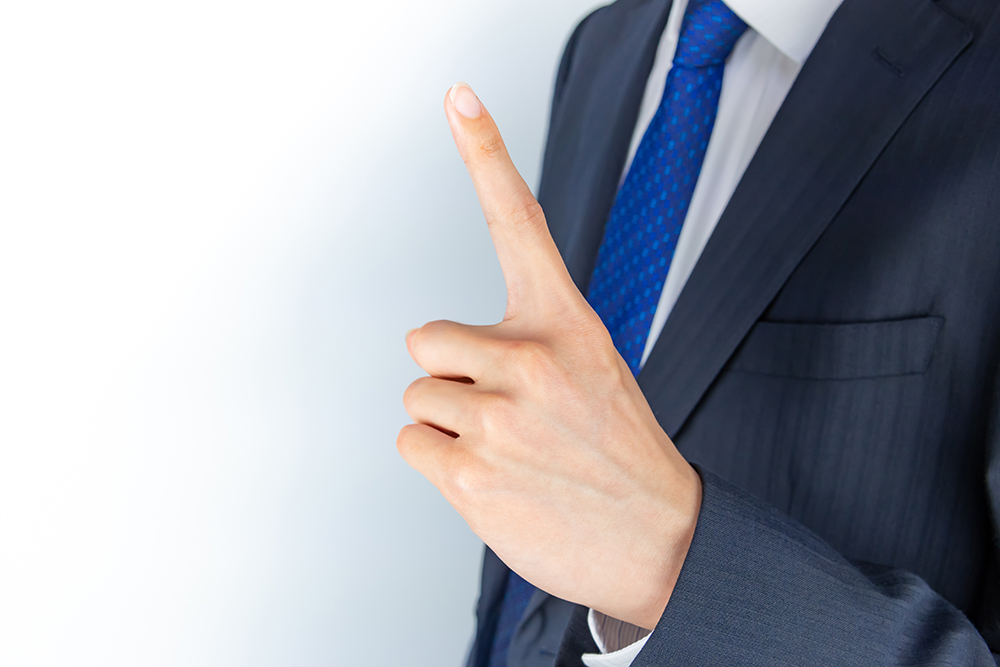 写真ACの無料登録で1日1枚だけダウンロードできることを示すイメージとして人差し指を立てたビジネスマンの写真