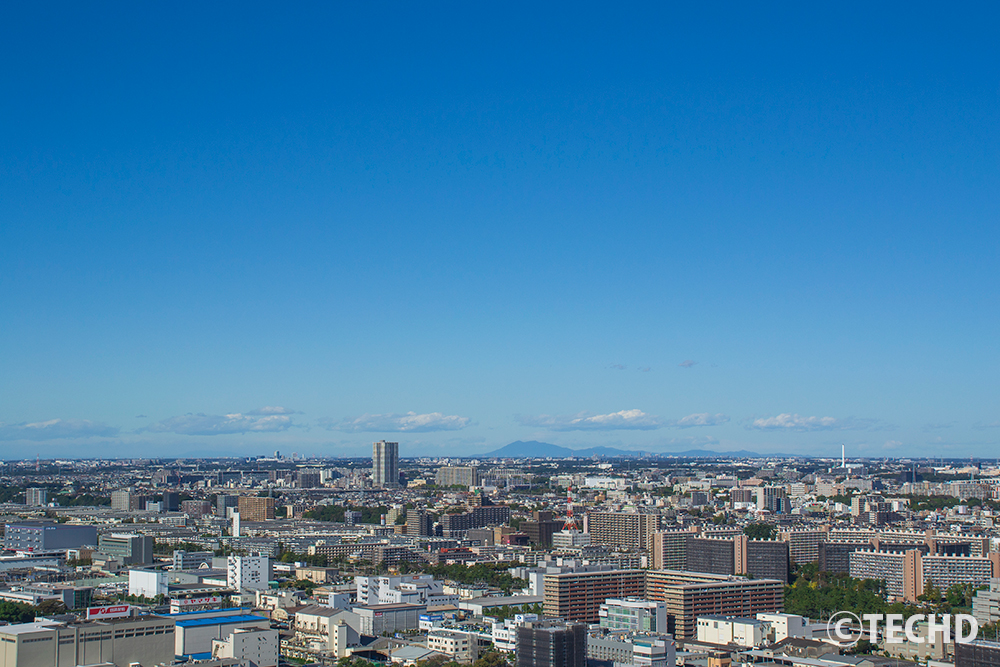 千葉県千葉市の街並みを高所から俯瞰で捉えた風景。地平線まで続く都市の景観と突き抜けるような青空。