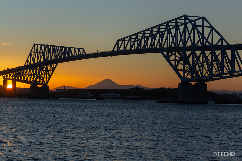 日没寸前。強烈な光がだんだん地平線へ消えていく瞬間。東京ゲートブリッジと富士山のシルエットが濃くなっていく。