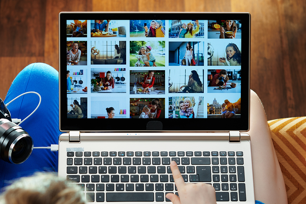 ノートパソコンで大量の写真素材を検索している様子。制作現場での素材探しに膨大な時間がかかる悩みを表現したイメージ画像。